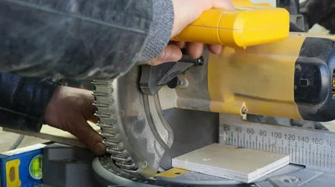 A worker saws the edge of a board on an end-cutting machine Fotos Stock