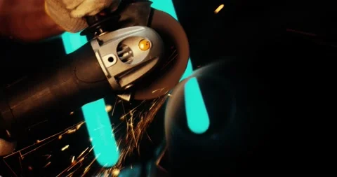 A worker saws a metal pipe using an angle grinder. Sheaves of beautiful sparks Video stock 167370407