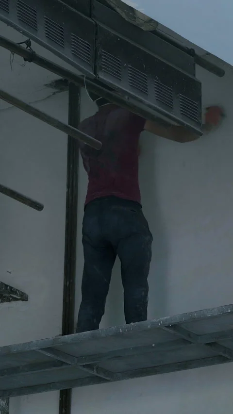 Worker on scaffolding applying plaster to a wall in a construction site Stock Footage 313928562