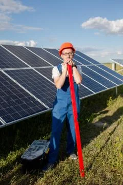 Worker with scale, solar panels behind him. Stock Photos