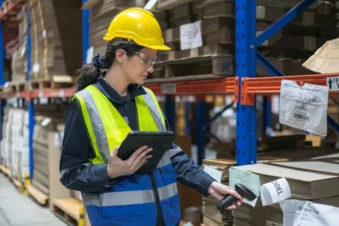 A worker scanning inventory in a warehouse using a tablet and barcode scann.. Foto stock
