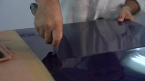 A worker scratches the surface of a perfectly painted car door Stock Footage 138276909