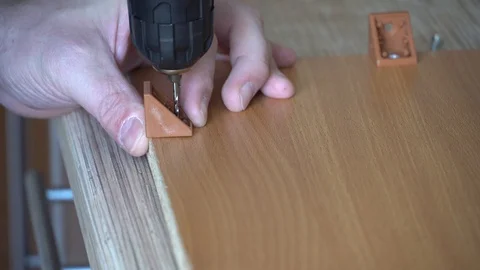Worker screwed a corner with a screwdriver to the board Stock Footage 124358484
