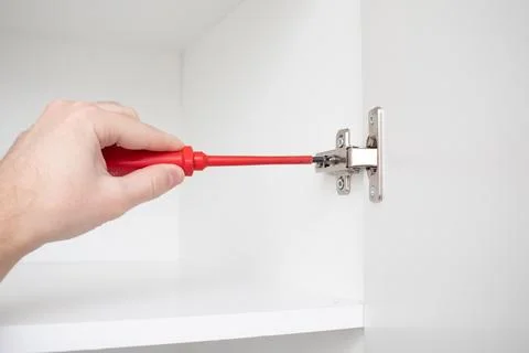 Worker screwing a wardrobe door to a hinge Stock Photos