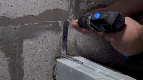 Worker screws a corner to the wall with a screwdriver Stock Footage 115420071
