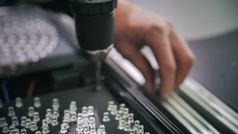 A worker screws on a matrix of traffic light LEDs at the factory. Close-up Stock-Footage 137580009
