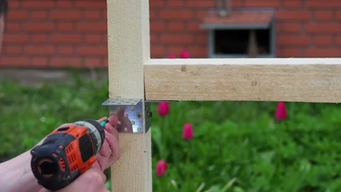 The worker screws the metal corner to the board with a screwdriver. Construct Stock Footage 195116644