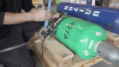 Worker secure gas tanks with straps. Stockbeeldmateriaal 90532110
