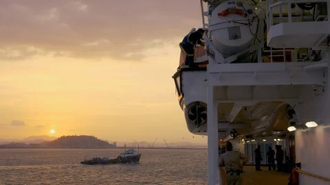 Worker secures tender boat Supply ship sails into sunset Video stock 108200358