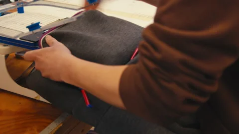Worker Securing Backpack in Embroidery Hoop for Custom Logo Stitching at Stock Footage 318727865