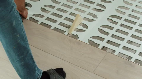 Worker Securing Decorative Flooring with Hammer and Spacer Stock Footage 321750169