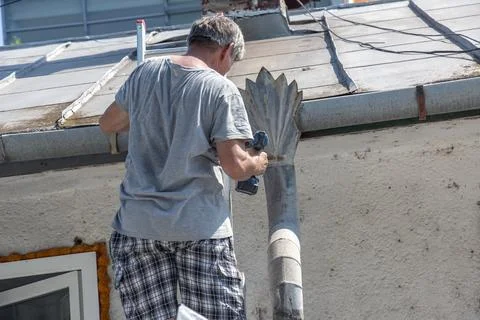 Worker Securing a Metal Downspout with a Cordless Drill Stock Photos