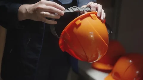 Worker selecting an orange safety helmet from a rack in warehouse Video stock 274434081