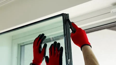 Worker separating triple glazed window glass unit into individual panels for Stockbeeldmateriaal 344519531