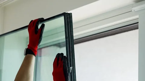 Worker separating triple glazed window glass unit into individual panels for Stockbeeldmateriaal 344519701