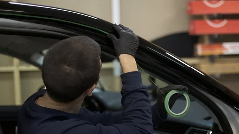 Worker at the service station paste vinyl in expensive car. Closeup protect film Stock Footage 121410130