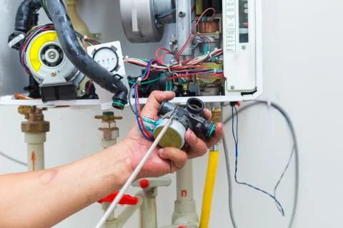 Worker set up central gas heating boiler at home Stock Photos