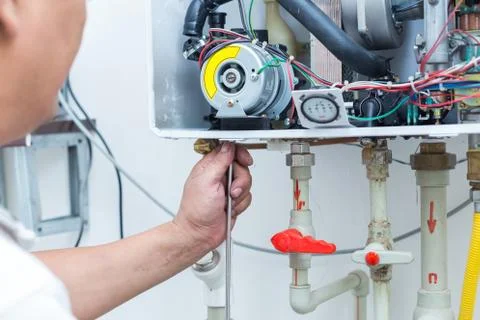 Worker set up central gas heating boiler at home Stock Photos