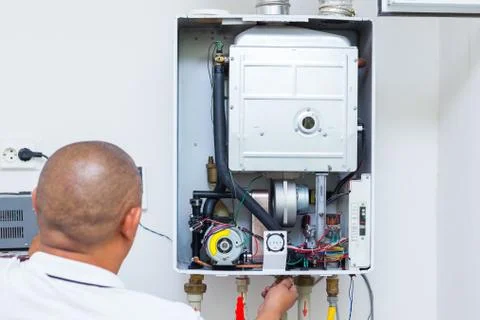Worker set up central gas heating boiler at home Stock Photos