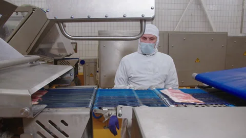 Worker sets up automated bacon cutter removal process in production facility Stock Footage 205488802