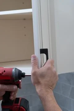 Worker sets handles for kitchen cabinets Stock Photos