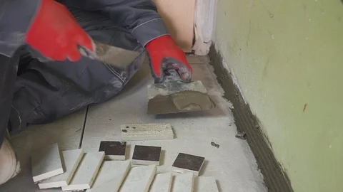 Worker sets small tiles on the wall in the kitchen. His hands are placing the Видео 102072373