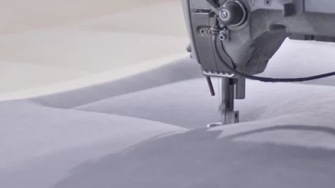 Worker sewing edges of mattress with help equipment in factory indoors. Stock-Footage 240757239