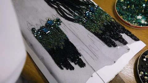 The worker of the sewing industry performs the work with beads on the fabric Stock Footage 93465672