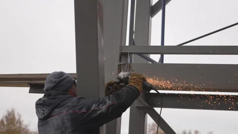 Worker shapes thick metal frame using fast sharp grinder Stock Footage 313833794
