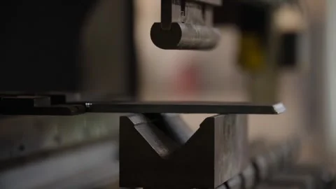 Worker shaping steel plate with precision on metal bending machine in workshop. Stock Footage 313815305