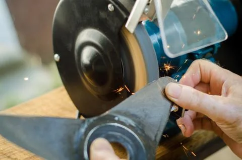 Worker sharpening his blade lawn mower. Stock Photos