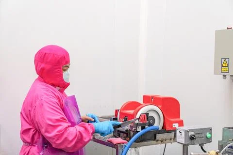 Worker sharpening the knife with a electric sharpener. Stock Photos