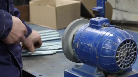 A worker is sharpening a threaded metal rod on a grinder Stock Footage 340558942