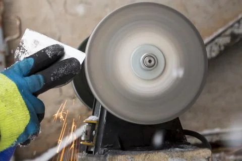 Worker sharpens a chisel on the emery wheel 스톡 사진