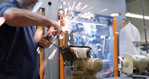 Worker shaving down a piece of metal in a factory Stock Footage 104000186