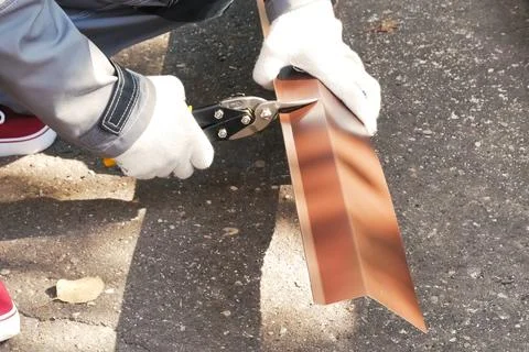 Worker shears sheet of roofing metal. Scissors for metal. Stock Photos