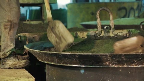 Worker with shovel dig shaking cement particles on metal cauldron lid Stock Footage 75643167
