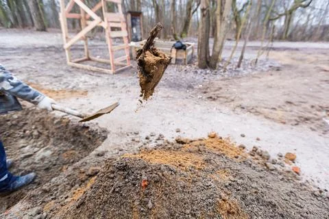 Worker with shovel is digging a pit on construction site. Concept of hard work Stock Photos