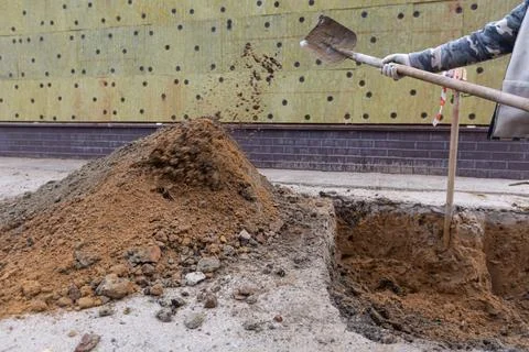 Worker with shovel is digging a pit on construction site. Concept of hard work Stock Photos