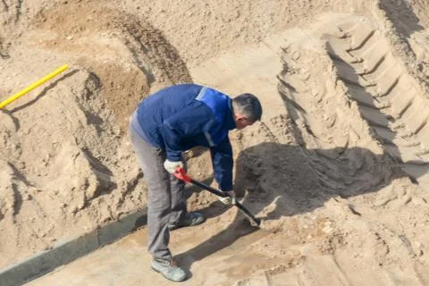 Worker with a shovel digging sand. Stock Photos