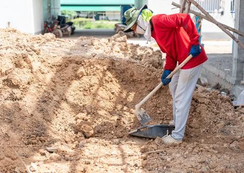 Worker with shovel loading soil in basket. Foto stock