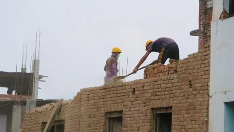 Worker with a shovel on the top storey of a partially destroyed house Stock Footage 77443880