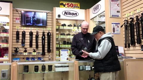 Worker showing used camera for customer inside Kerrisdale cameras store Stock Footage 68899365