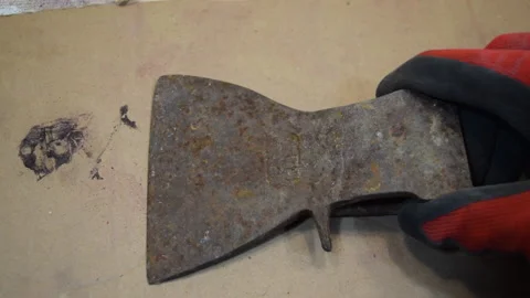 A worker shows an old rusty axe. Restoration of a rusty axe. Stock Footage 156339936