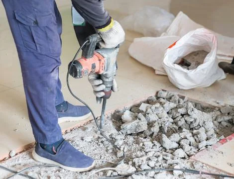 The worker is sitting on the floor to remove the tiles. Stock Photos