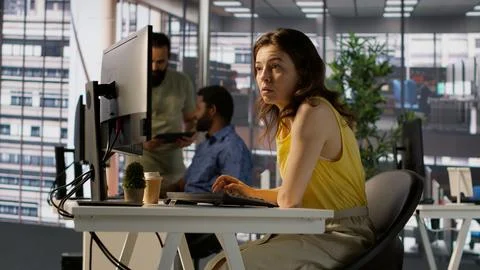 Worker sitting at office desk using computer during job shift Stock Photos