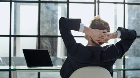 Worker sitting in office with hands behind his head Stock Photos