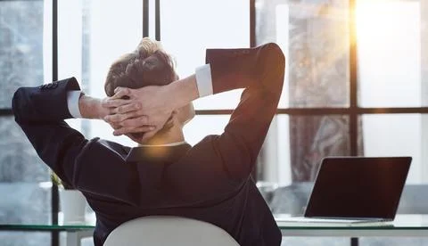 Worker sitting in office with hands behind his head Stock Photos