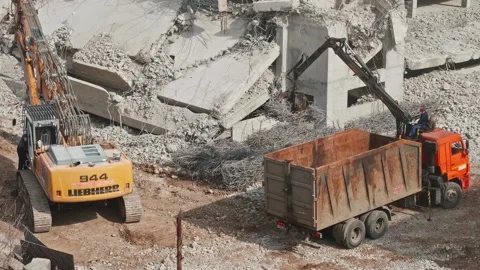 Worker is sitting on tip truck controlling the hoe and is moving armature from Stock Footage 153011150