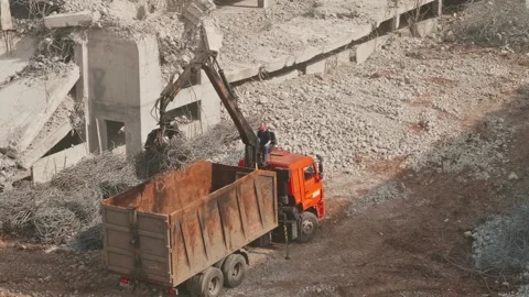 Worker is sitting on tip truck controlling the hoe and is moving armature from Stock Footage 153011155